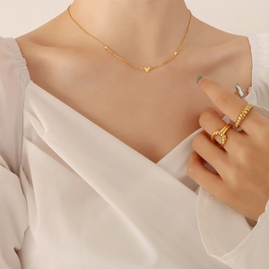 Minimalist gold heart necklace and rings set worn by model in elegant white shirt