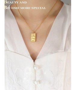 Close-up of gold portrait coin pendant with Venus engraving on bead chain necklace