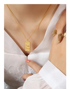 Close-up of gold plated portrait pendant necklace and butterfly ring on white embroidery