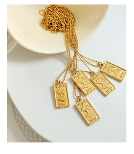 Macro detail of gold-plated rectangle Venus 1990 pendant on thin bead chain necklace