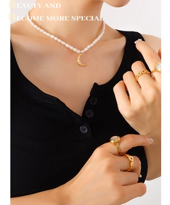 Detail of 18K gold-plated moon pendant necklace with freshwater pearls on a model