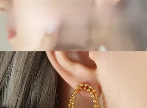 Detail of elegant gold beaded double-layer earrings with freshwater pearl accents