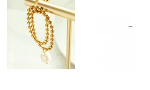 Detail of double-layer gold bead chain earring with elegant white teardrop pearl drop