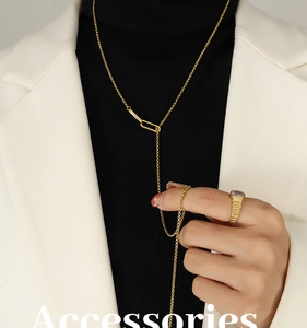 Gros plan d'un collier en Y doré avec maillon géométrique et bague en diamant nervurée