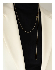 Détail d'un long collier doré ajustable avec glands géométriques porté par un mannequin
