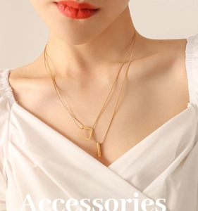 Close-up of a double-layered gold geometric necklace featuring square and bar pendants