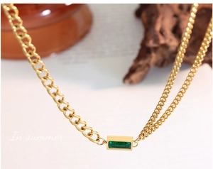 Detail of gold chain necklace with rectangular emerald green gemstone and asymmetrical links