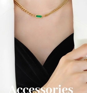 Detail of double-layer gold chain necklace with emerald green zircon on model