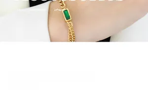 Close-up of gold chain bracelet featuring a rectangle emerald green stone on wrist
