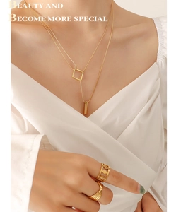 Detail of layered gold geometric square necklace and textured rings on model
