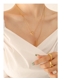 Close-up of layered gold geometric square pendant necklaces and minimalist rings on model
