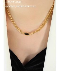 Detail of layered gold-plated chain necklace with a rectangular black gemstone pendant