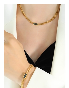 Detail of a gold plated necklace and bracelet set featuring a black zircon stone inlay