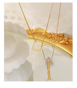 Detailed macro view of layered gold-plated square and bar pendants on sleek snake chains