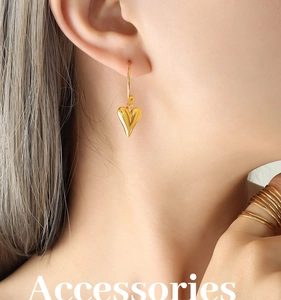 Détail de boucles d'oreilles cœur dorées et bague assortie sur modèle en lumière douce