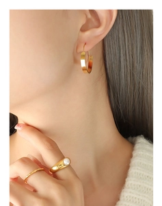 Detailansicht goldener Creolen und klobiger Ring mit weißer Perle an einem Model
