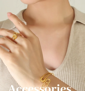 Detail view of gold safety pin style adjustable bracelet and ring set on model
