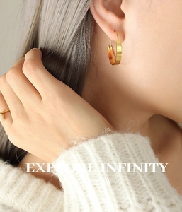 Nahaufnahme goldener Creolen und eines minimalistischen Rings an einem Modell
