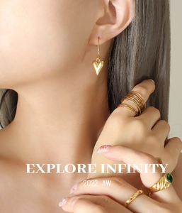 Gros plan de boucles d'oreilles cœur dorées et bagues vintage avec pierres vertes