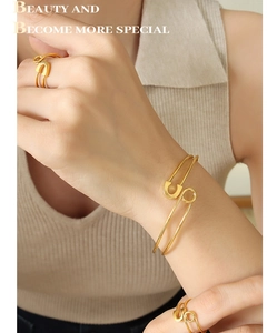 Detail of gold safety pin style adjustable bracelet and rings jewelry set on model