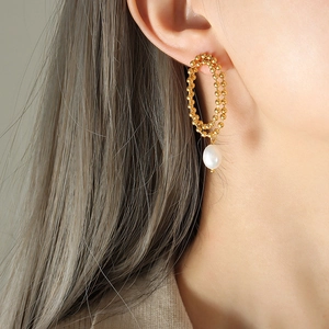Elegant gold beaded double-layer oval earrings with freshwater pearl drop on a model