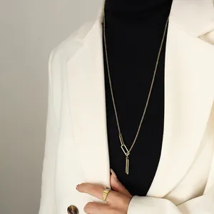 Long collier doré avec pendentif géométrique et bague sertie d'une pierre sur le mannequin