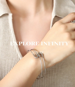 Close-up of a silver safety pin bracelet and ring set worn on a model wrist
