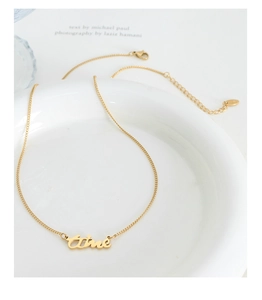 Détail du pendentif doré aime avec chaîne réglable sur un plateau en céramique blanche