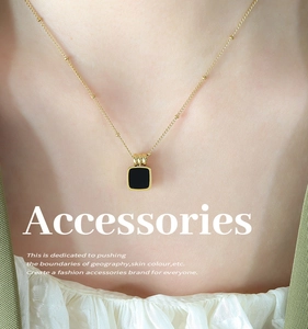 Detail of gold bead chain necklace with black square pendant on a female model