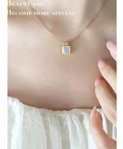 Detail of gold satellite chain with square grey shell pendant on female neck