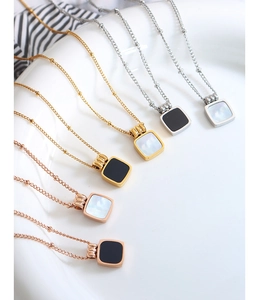 Detail of square pendants with black onyx and white shell on 18K gold plated bead chains