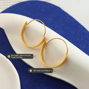 Minimalistische Creolen aus 18K vergoldetem Edelstahl auf blauem Texturhintergrund