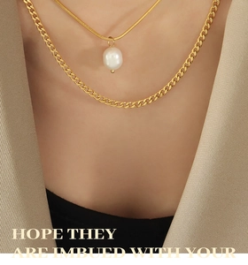 Close-up of a layered gold necklace featuring a freshwater pearl and flat Cuban link chain