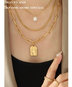 Detail of layered gold necklaces with pearl, Cuban links and rectangular portrait pendant
