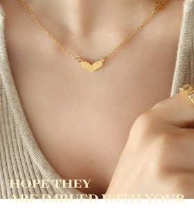 Detailed close-up of a gold heart pendant with Love engraving worn by a model