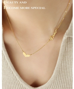 Detail of gold titanium steel necklace with heart and Love pendant on woman's neck