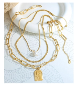 Close-up of triple-layered gold necklaces with pearl and portrait pendant details
