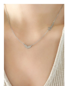 Detail of silver heart pendant with Love engraving and artistic script on a chain