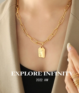 Detail of gold layered chain featuring an abstract face profile relief on a square pendant