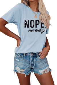 Détail du t-shirt bleu clair avec imprimé NOPE et short en jean déchiré