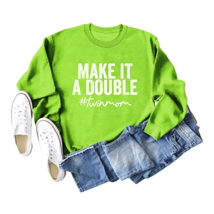 Flat lay of bright green sweatshirt with 'MAKE IT A DOUBLE #twinmom' print and jeans