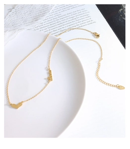 Close-up of gold titanium steel heart necklace with Love engraving and K18 tag detail