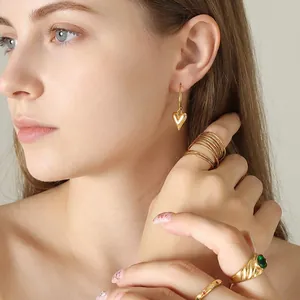 Boucles d'oreilles cœur dorées minimalistes au fini poli portées par un mannequin