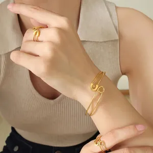 Gold safety pin jewelry set featuring adjustable open bracelet and matching rings for women