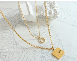 Detail of double-layer gold necklace with YOU & ME engraved square pendant and heart charms