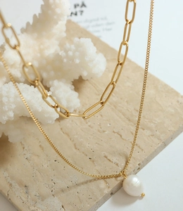 Gros plan sur collier doré à mailles trombone et pendentif perle de culture baroque