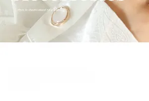 Detailed close-up of a large white pearl button with a gold metal rim on satin fabric