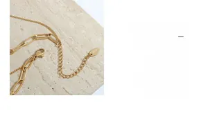 Détail du collier doré à plusieurs rangs avec maillons trombone et breloque gravée K18