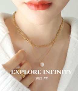Gros plan d'un collier à maillons trombone dorés multicouche avec pendentif en perle