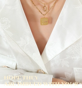 Detail of double-layer gold titanium necklace with 'YOU & ME' engraved square pendant